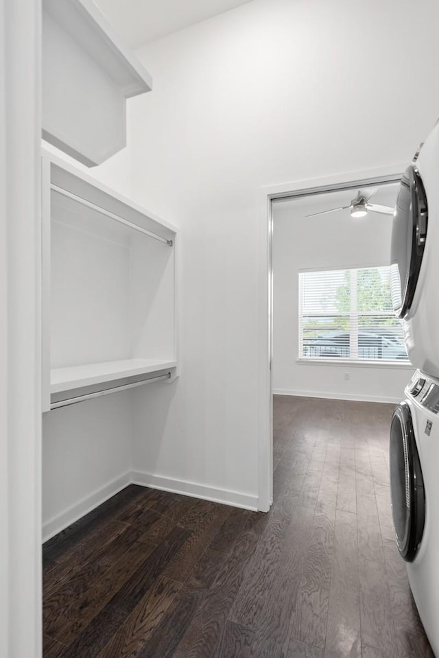 laundry room featuring baseboards, laundry area, stacked washer and clothes dryer, dark wood-style floors, and a ceiling fan