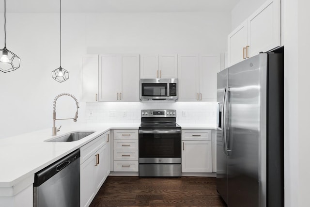 kitchen featuring a peninsula, a sink, stainless steel appliances, light countertops, and backsplash