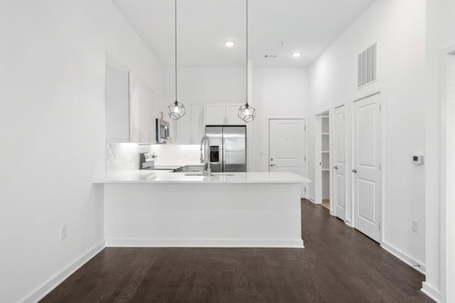 kitchen with visible vents, a peninsula, dark wood-style flooring, appliances with stainless steel finishes, and white cabinetry