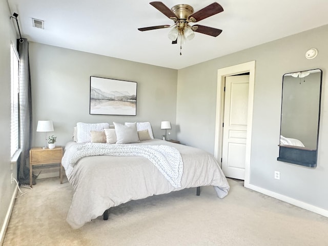 bedroom featuring visible vents, baseboards, light colored carpet, and a ceiling fan