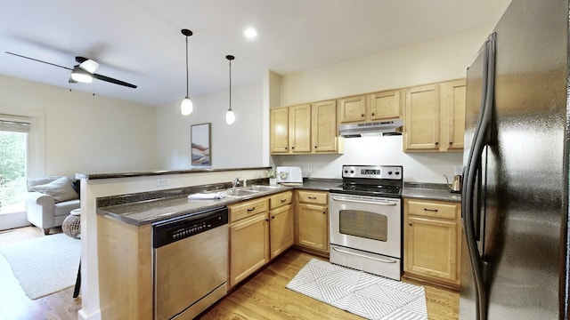 kitchen featuring light brown cabinets, a peninsula, stainless steel appliances, under cabinet range hood, and dark countertops