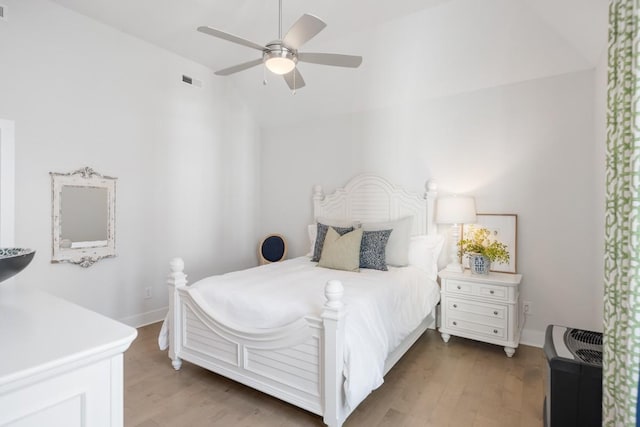 bedroom with ceiling fan, visible vents, baseboards, and wood finished floors