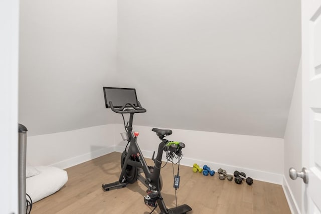 workout room with baseboards, wood finished floors, and vaulted ceiling