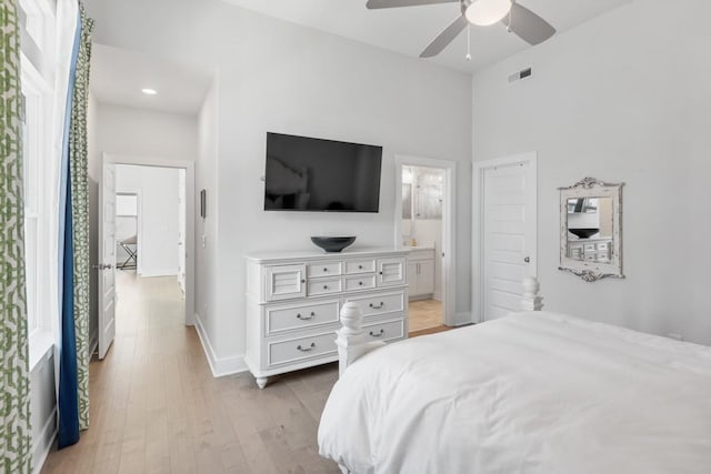 bedroom featuring baseboards, visible vents, light wood-style flooring, ceiling fan, and ensuite bathroom