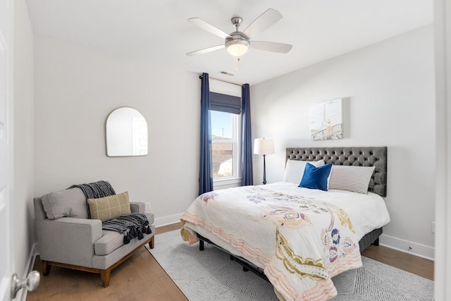 bedroom featuring visible vents, ceiling fan, baseboards, and wood finished floors