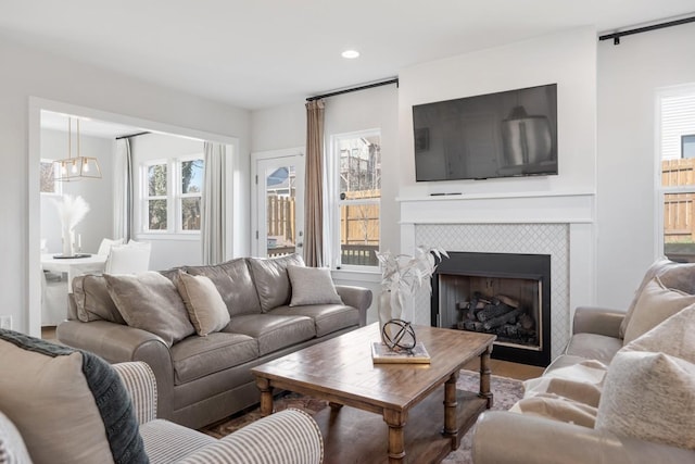 living area with a tiled fireplace, recessed lighting, and an inviting chandelier