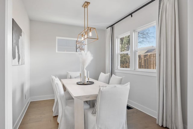 dining space featuring a notable chandelier, wood finished floors, and baseboards