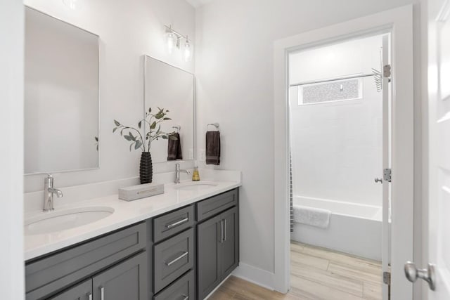 bathroom featuring a sink, shower / bath combination, wood finished floors, and double vanity