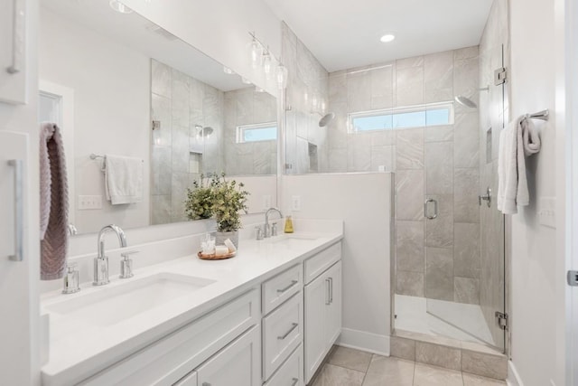 full bath with a sink, baseboards, a stall shower, and double vanity