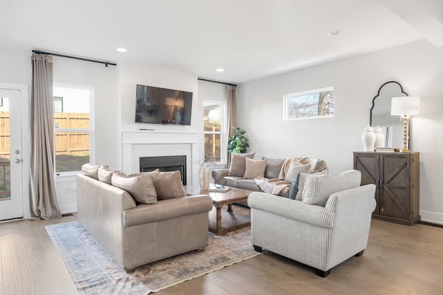 living area with a tiled fireplace, recessed lighting, and light wood-style flooring