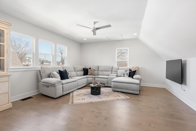 living room with vaulted ceiling, wood finished floors, visible vents, and baseboards