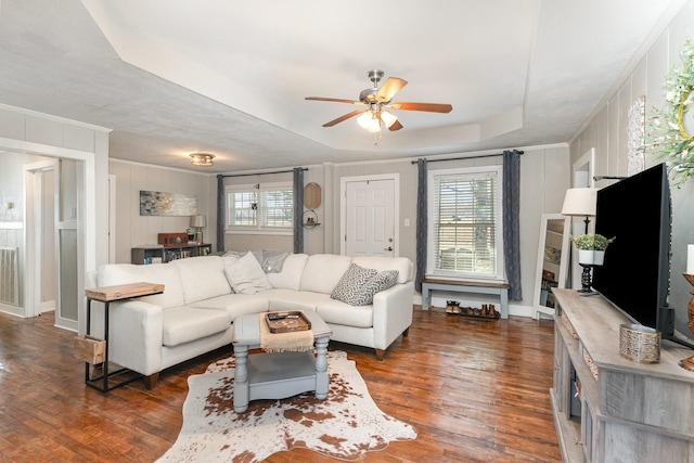 living area with visible vents, ceiling fan, ornamental molding, wood finished floors, and a raised ceiling