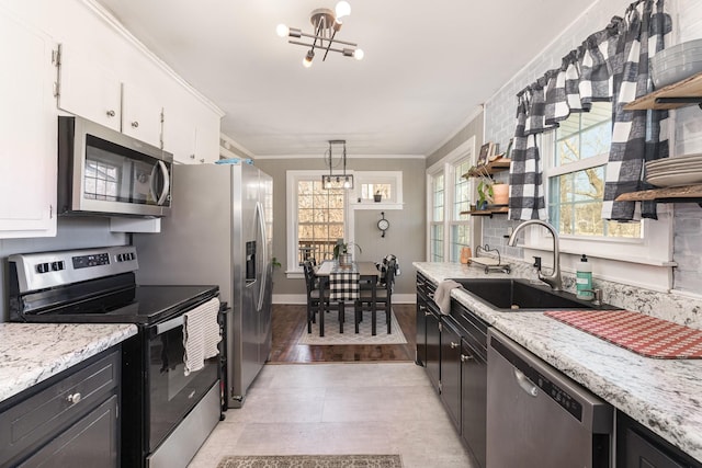 kitchen featuring an inviting chandelier, open shelves, appliances with stainless steel finishes, and a sink