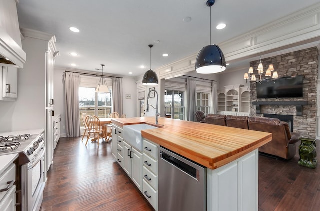 kitchen with white cabinets, stainless steel appliances, wood counters, and a sink