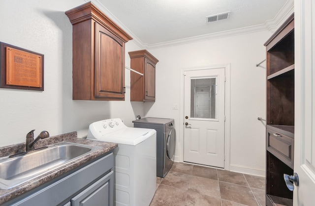 washroom with visible vents, crown molding, separate washer and dryer, cabinet space, and a sink