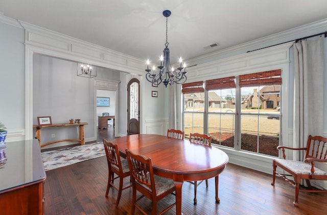 dining space featuring crown molding, a decorative wall, visible vents, and a chandelier