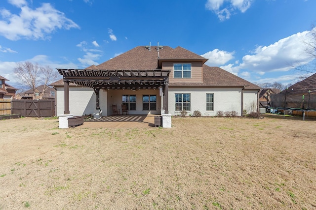 rear view of house with fence, a trampoline, brick siding, and a patio area