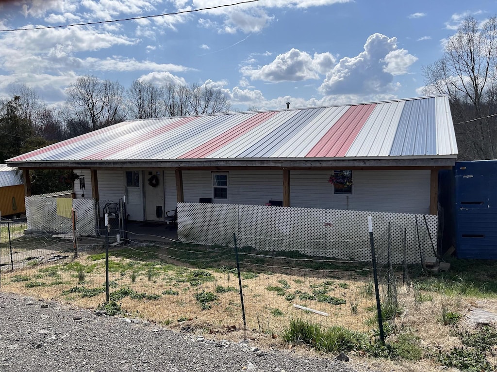 view of front of house featuring metal roof and fence