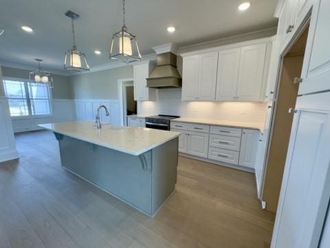 kitchen with a wainscoted wall, custom exhaust hood, electric range oven, white cabinetry, and crown molding