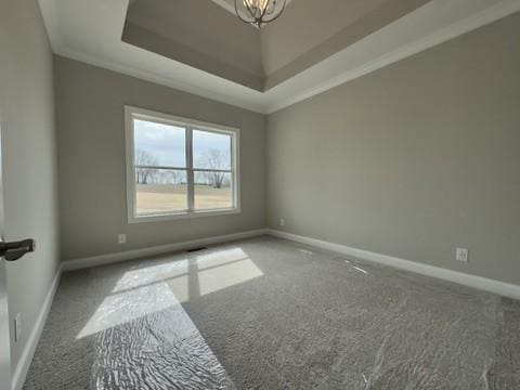 spare room with an inviting chandelier, a tray ceiling, carpet, and baseboards