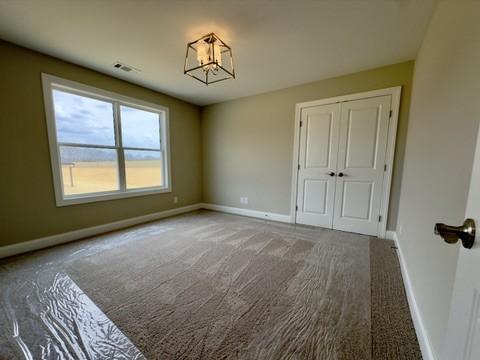 carpeted spare room featuring baseboards and a notable chandelier