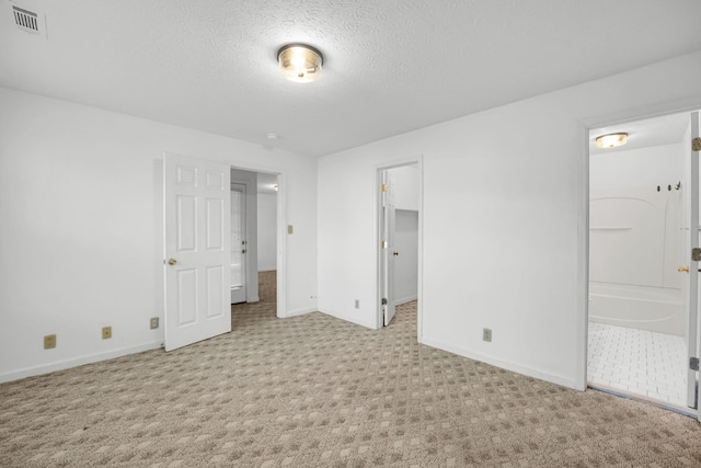 unfurnished bedroom with visible vents, baseboards, carpet flooring, ensuite bathroom, and a textured ceiling