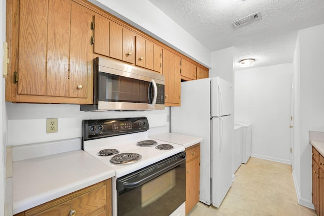 kitchen featuring stainless steel microwave, visible vents, light countertops, electric stove, and separate washer and dryer