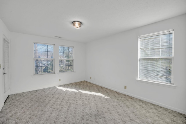 carpeted spare room featuring visible vents and baseboards