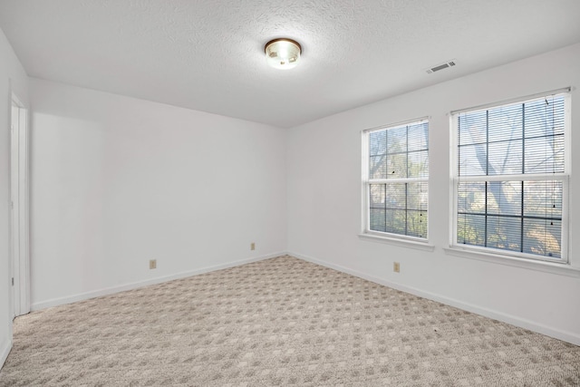 unfurnished room featuring baseboards, visible vents, a textured ceiling, and carpet