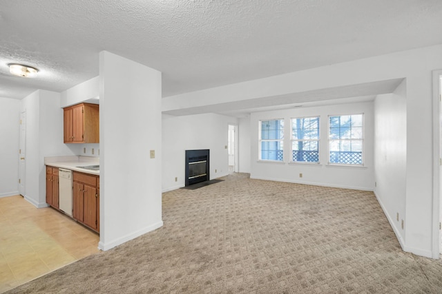 unfurnished living room featuring light carpet, a fireplace with flush hearth, a textured ceiling, and baseboards