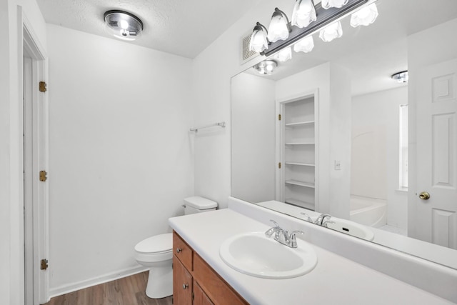 full bathroom with visible vents, toilet, a textured ceiling, wood finished floors, and vanity