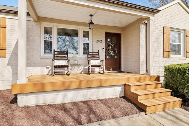 doorway to property with brick siding and a porch