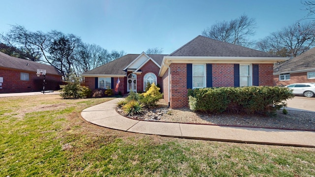 view of front of house with a front lawn, brick siding, and a shingled roof