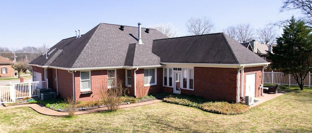 back of house with brick siding, a yard, and a garage