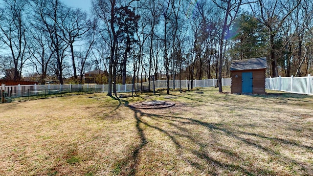 view of yard featuring a storage unit, an outdoor structure, a fenced backyard, and an outdoor fire pit