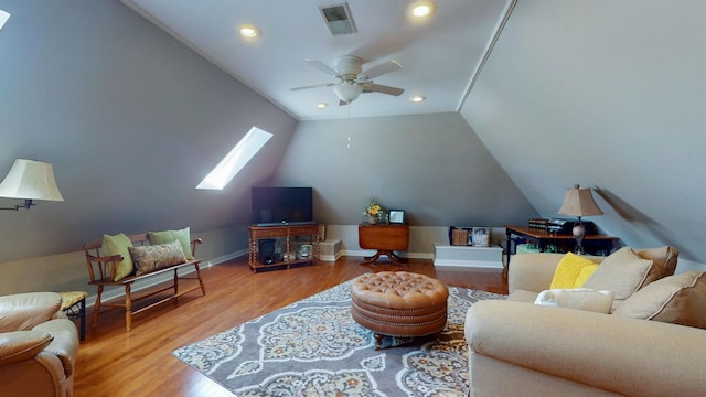 living room featuring visible vents, lofted ceiling with skylight, a ceiling fan, wood finished floors, and baseboards