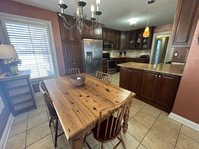 kitchen with dark brown cabinetry, light tile patterned floors, backsplash, and appliances with stainless steel finishes