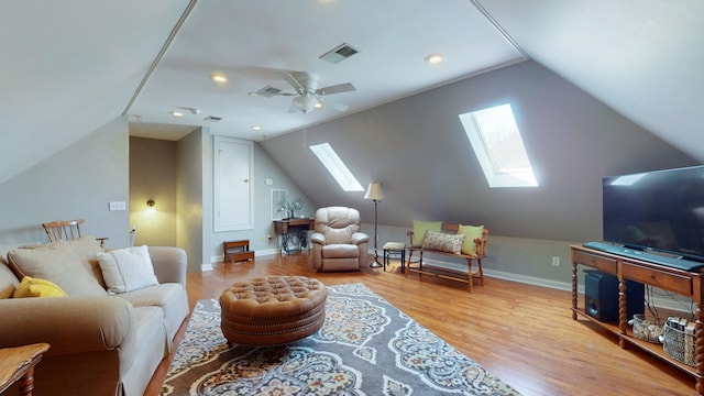 living area featuring visible vents, baseboards, ceiling fan, vaulted ceiling with skylight, and light wood-style flooring