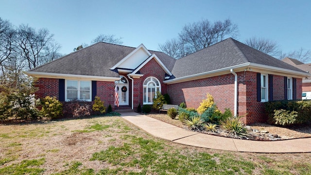 traditional-style home with a front yard, brick siding, and a shingled roof