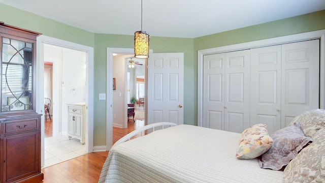 bedroom with multiple windows, light wood-style floors, a closet, and baseboards