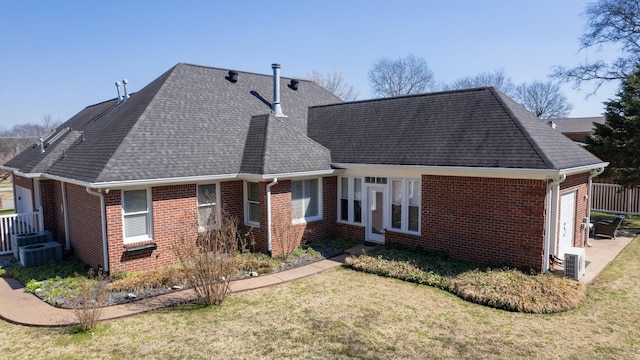 back of property featuring a yard, brick siding, roof with shingles, and an attached garage