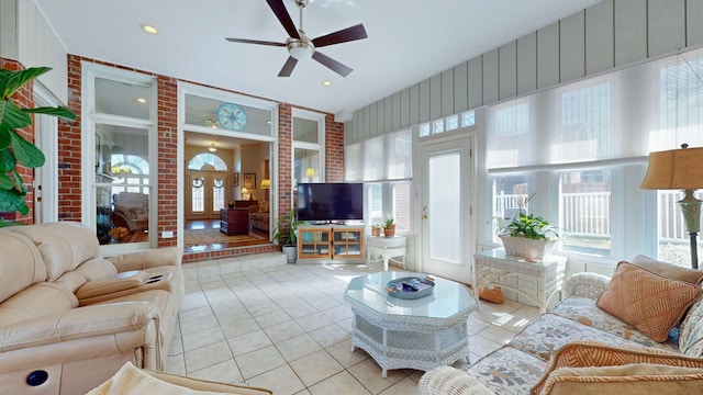 living area with a wealth of natural light, tile patterned floors, and ceiling fan