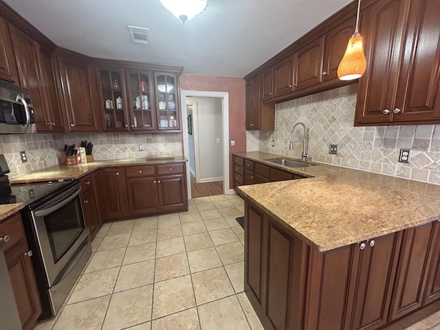 kitchen with light tile patterned flooring, stainless steel appliances, a sink, glass insert cabinets, and tasteful backsplash