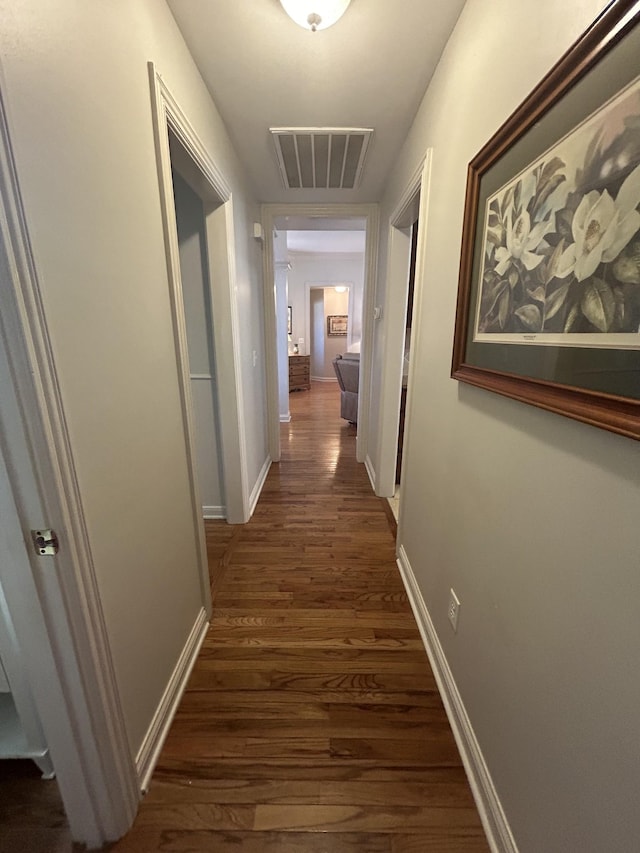 corridor with visible vents, baseboards, and dark wood finished floors