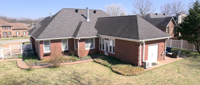 back of property with a lawn, fence, roof with shingles, a garage, and brick siding