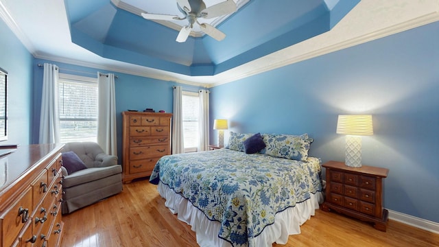 bedroom featuring a tray ceiling, baseboards, light wood-style flooring, and ornamental molding