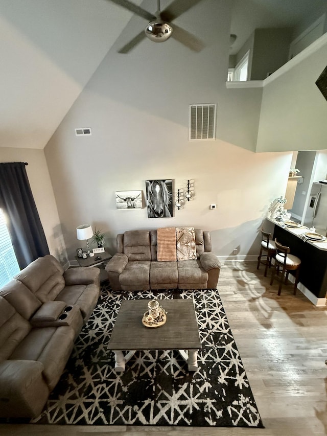 living room featuring visible vents, wood finished floors, high vaulted ceiling, and ceiling fan