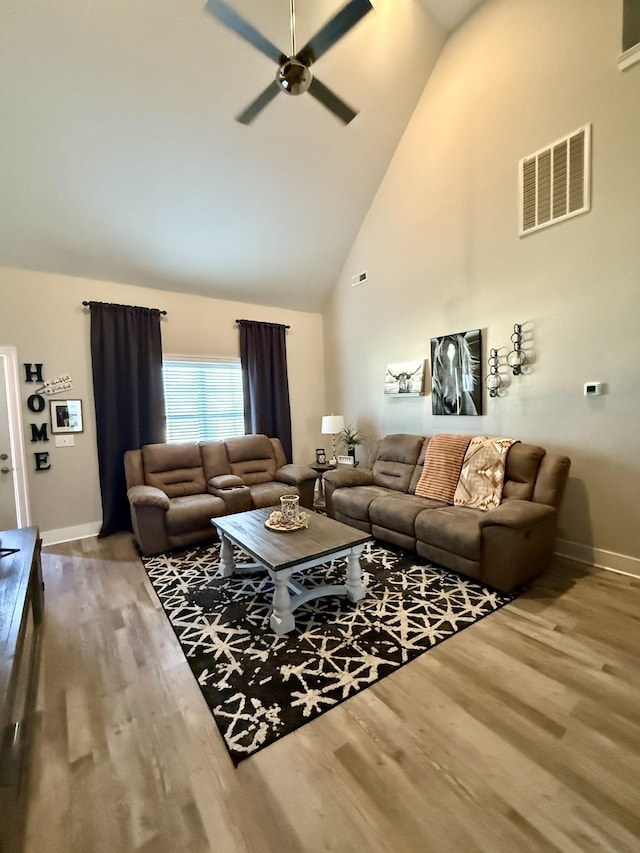 living area with high vaulted ceiling, wood finished floors, visible vents, and ceiling fan