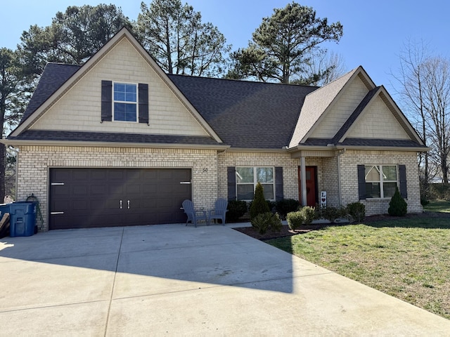 craftsman inspired home featuring driveway, a shingled roof, a front lawn, a garage, and brick siding