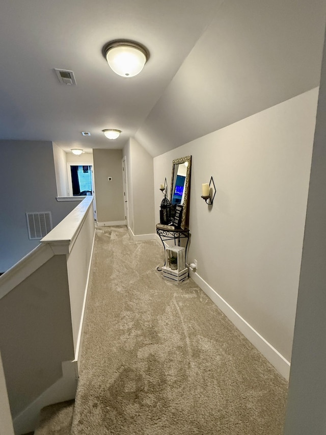 hall with visible vents, an upstairs landing, light colored carpet, and baseboards